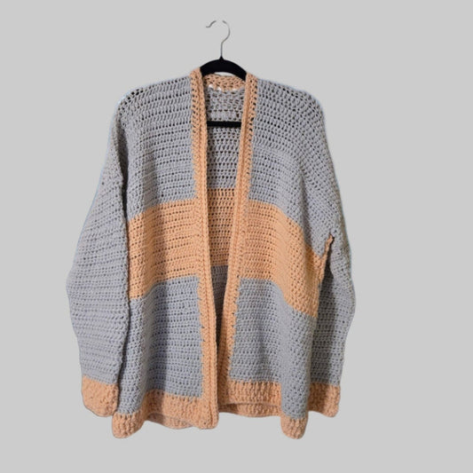 Coral and gray sweater cardigan against a cloudy sky backdrop.