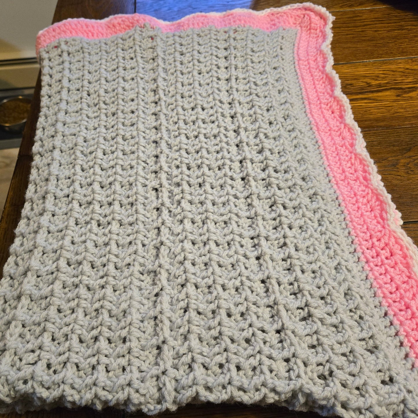 Handmade oversized baby blanket in light gray with pink border, cozy and warm crib blanket