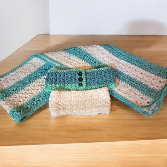 Handmade scarf with two winter headbands, white and green with buttons, on wooden surface.