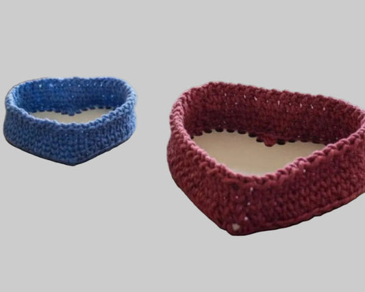 Handmade heart-shaped macrame baskets in blue and red on wooden table for home decor and organization