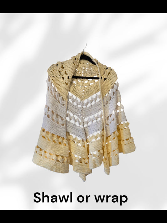Handmade crocheted yellow and white shawl or wrap hanging on a hanger.