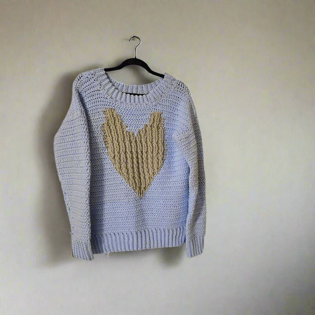 Blue pull over sweater with long sleeves and tan heart emblem, size medium.