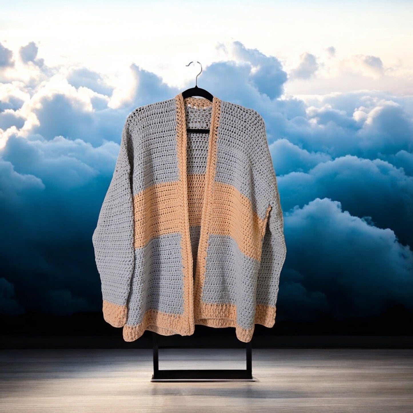 Coral and gray sweater cardigan against a cloudy sky backdrop.