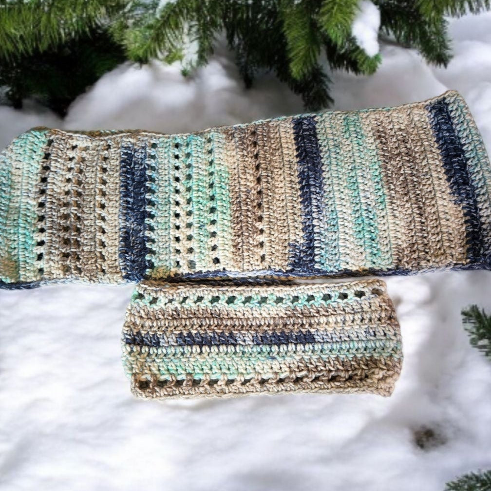 Multicolored handmade scarf and winter headband set displayed on snow.