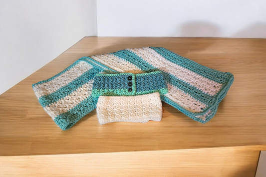 Handmade scarf with two winter headbands, white and green with buttons, on wooden surface.