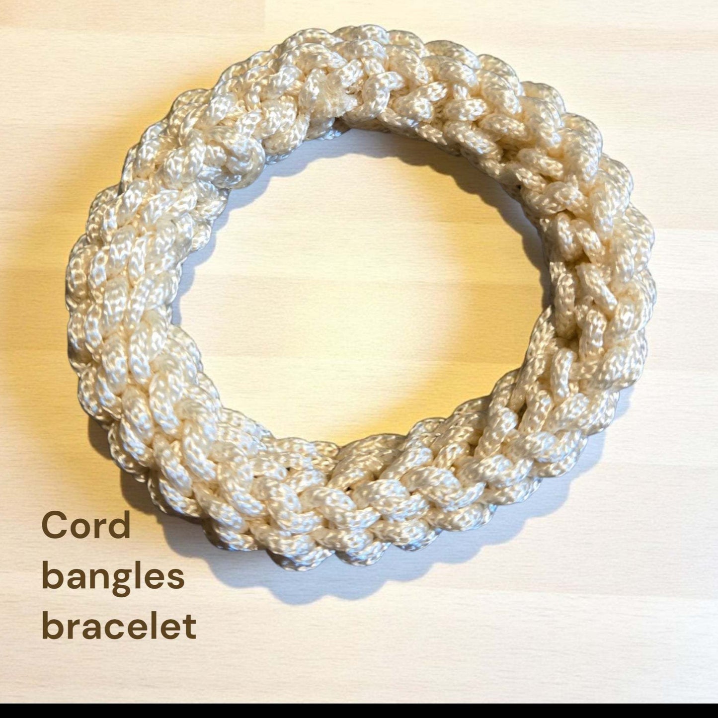 Cord bangles bracelet on a light wooden surface
