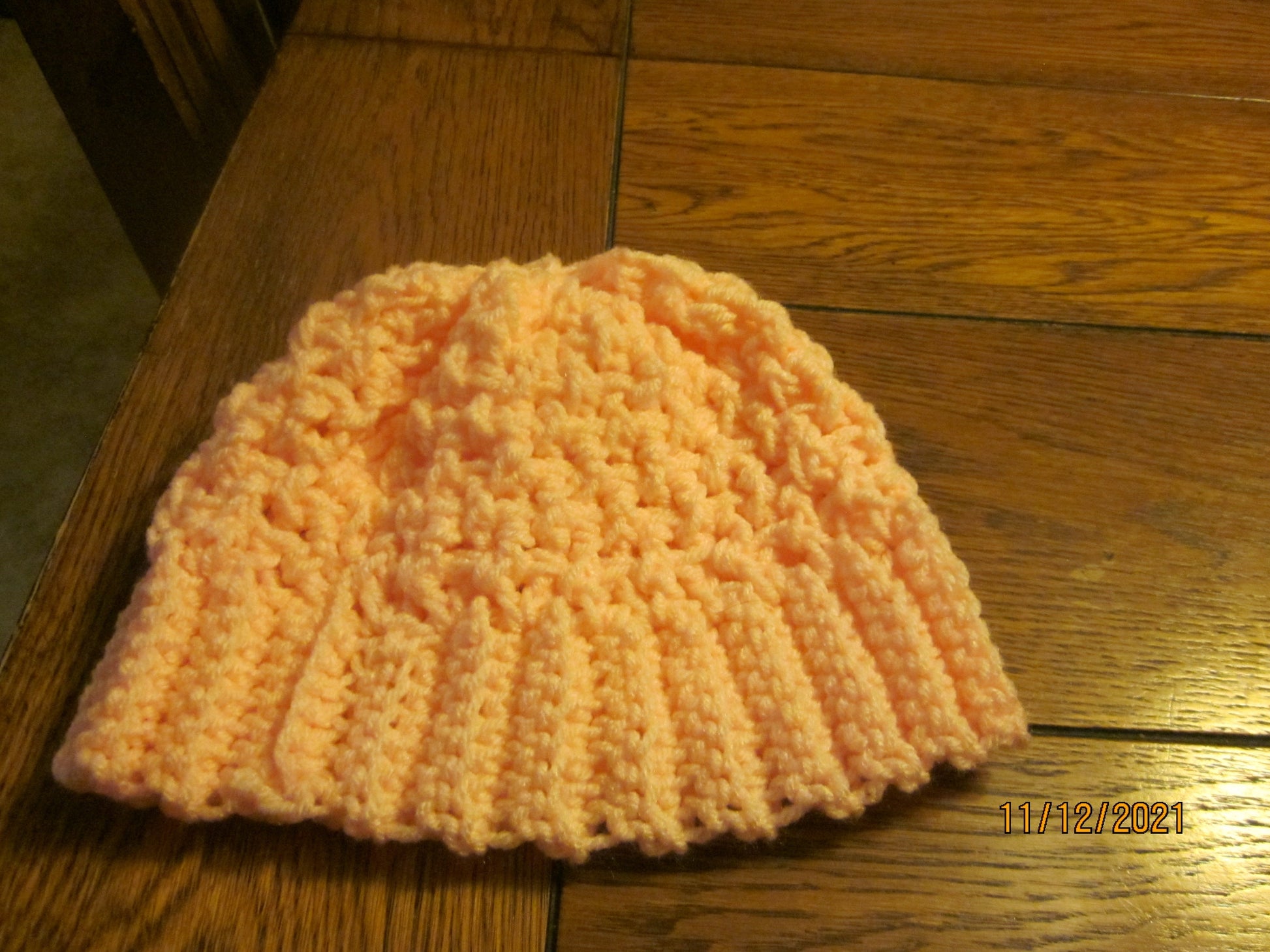 Handmade yellow and white winter beanie, 22-inch circumference, 8-inch height, on wooden surface.