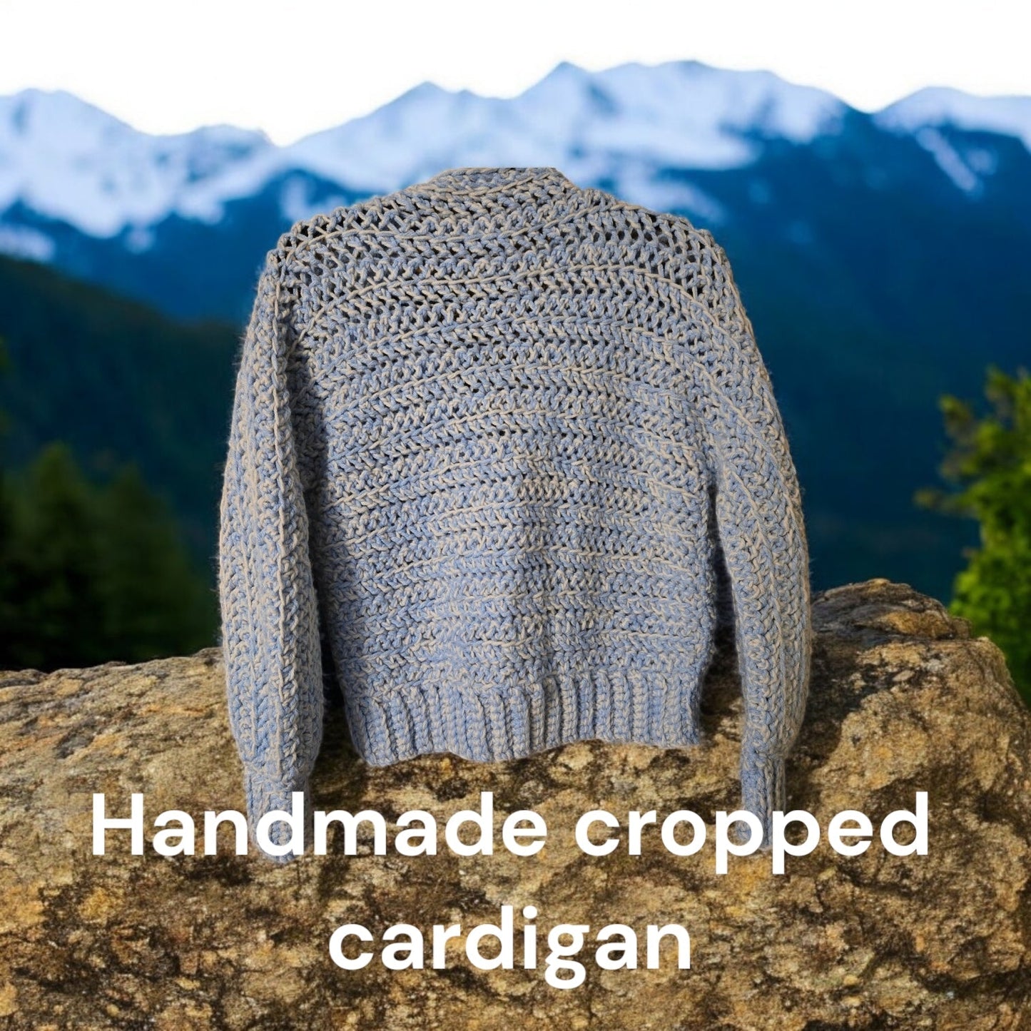 Handmade blue and white women's crop cardigan on rock background.