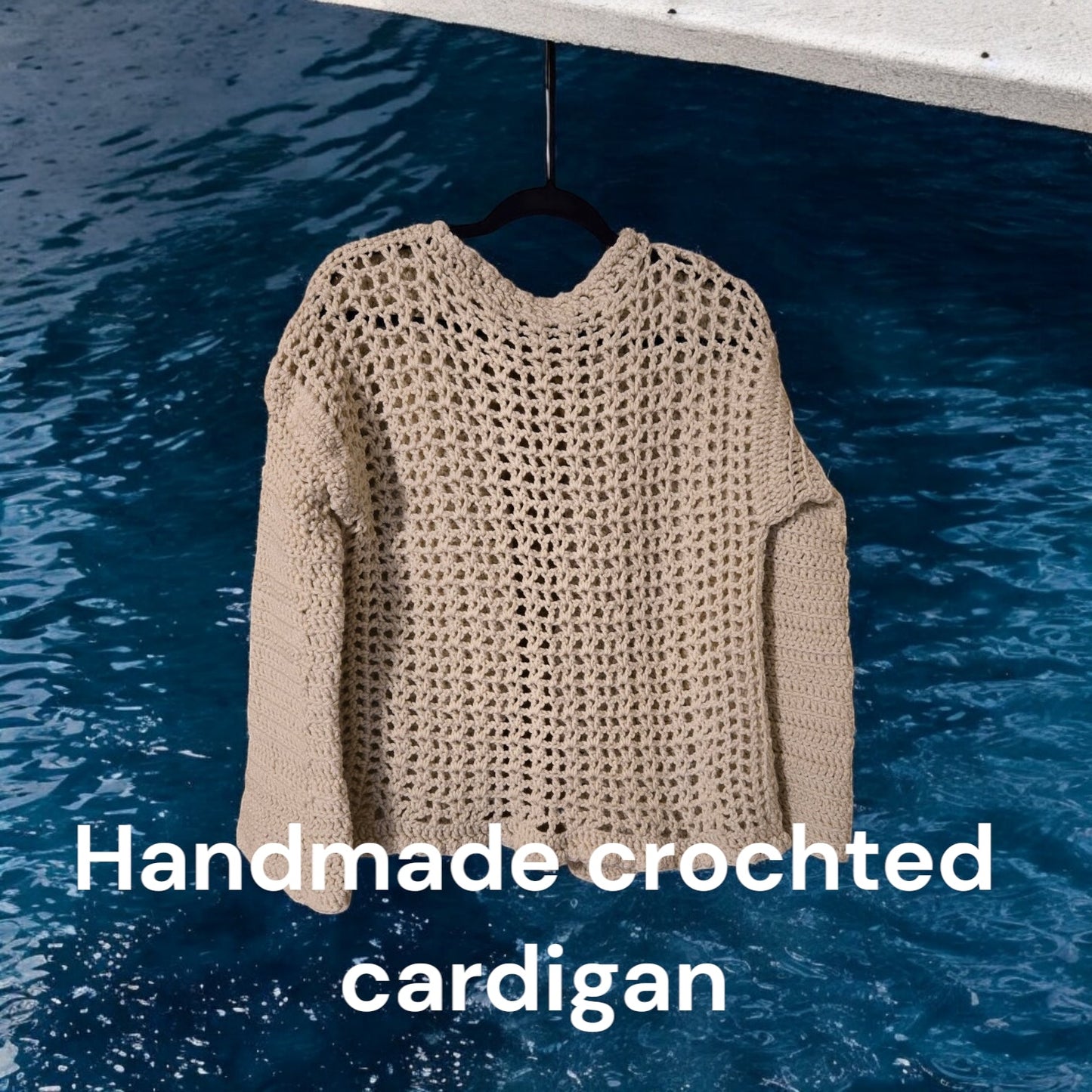 Handcrafted tan cardigan with bell sleeves hanging against a blue background.