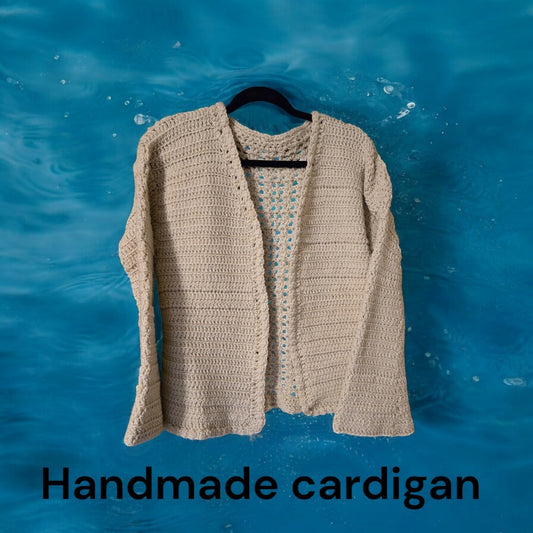 Handcrafted tan cardigan with bell sleeves against blue background.