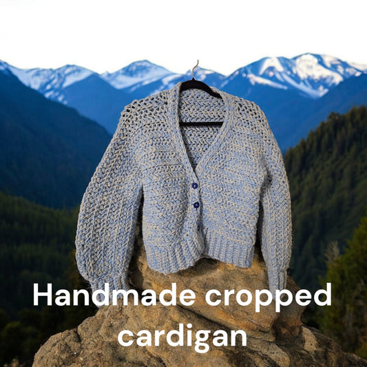 Handmade blue and white women's crop cardigan with button closure displayed outdoors.