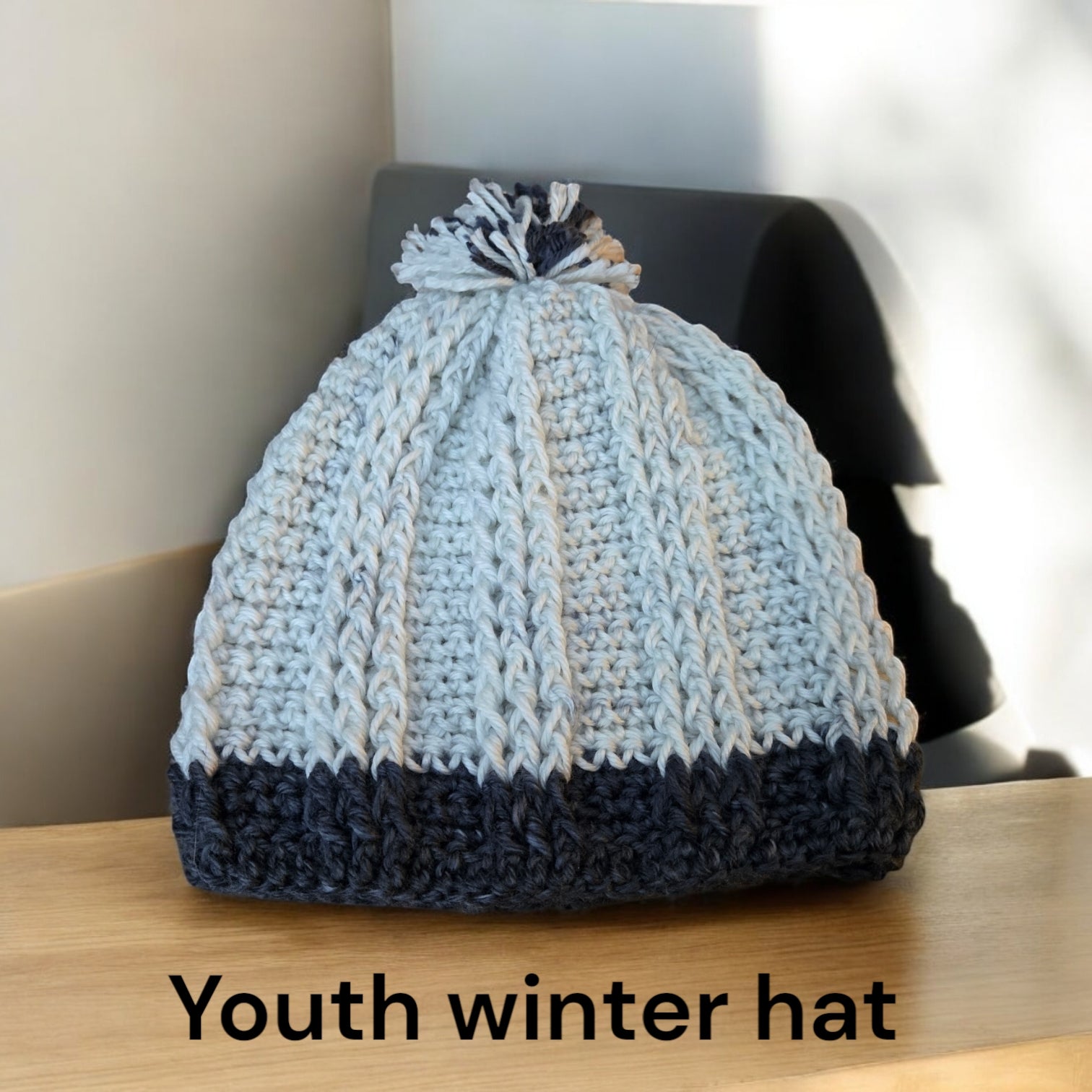 Child youth winter hat in cream and gray crochet design on a table.