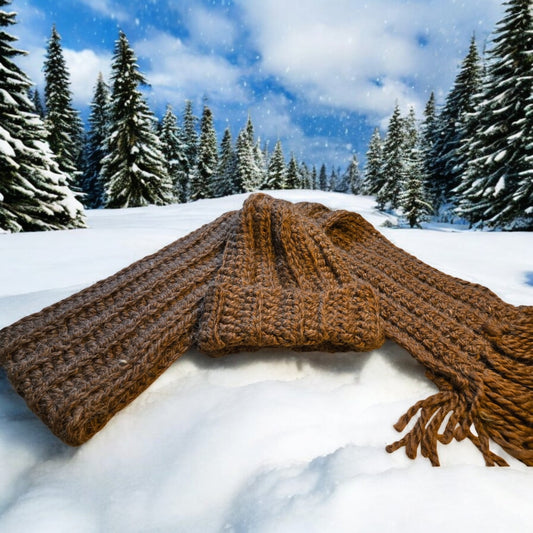 Winter handmade hat and scarf set on snowy background, crocheted from wool yarn.