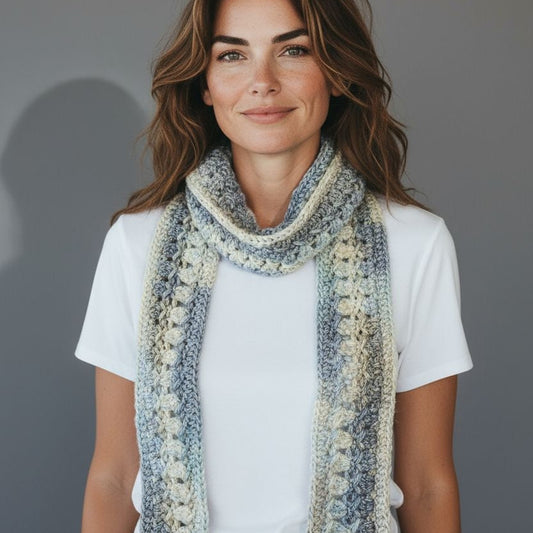 Model wearing a decorative scarf multi-colored in blues, gray and cream.