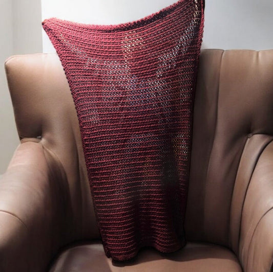 Handmade maroon Afghan blanket draped over a brown leather chair.