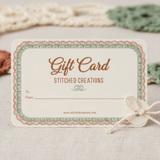 Gift card with 'Stitched Creations' branding on a textured surface with crochet items.